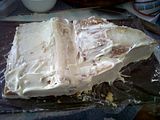 Birthday cake: Crumb layer, One loaf of lemonade cake, triangles sliced off right end, reversed & added to left. One 8" square, (baked slightly off-level), 2" cut from left (shallow) end, stacked on right, cut to a slight curve. All held together with frosting. Coated w/ layer of frosting to seal crumbs in. Returned to freezer.